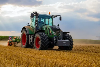 big green tractor driving in a field