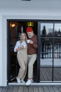 older couple holding mugs in doorway